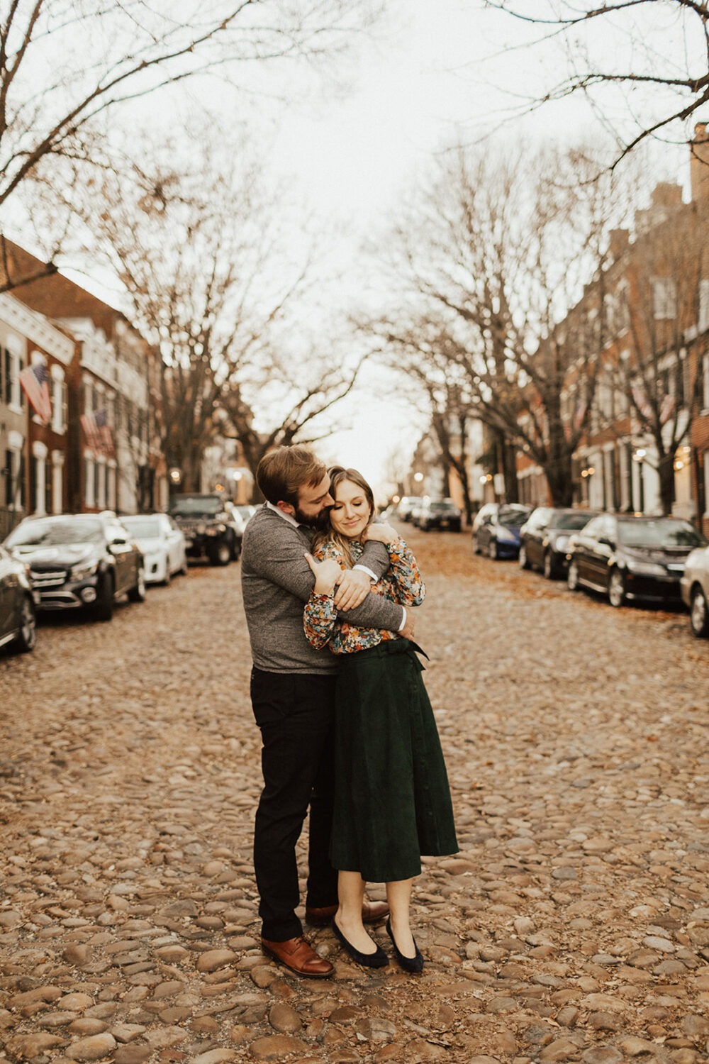 couple embraces on cobblestone street at engagement session