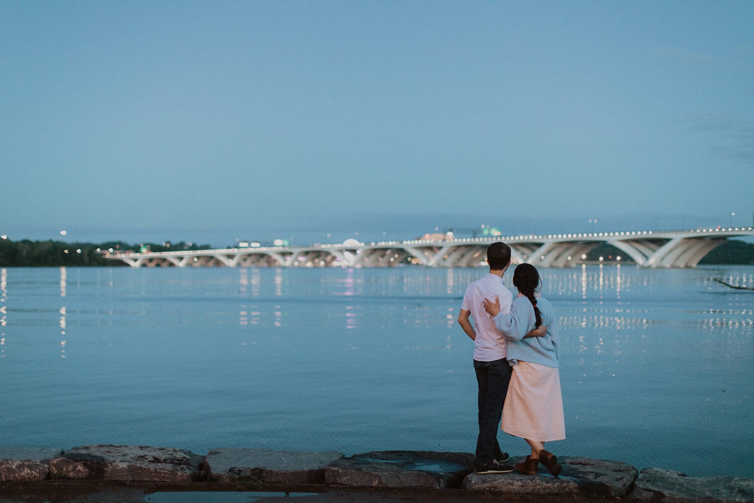 couple embraces by water at Old Town Alexandria waterfront engagement session