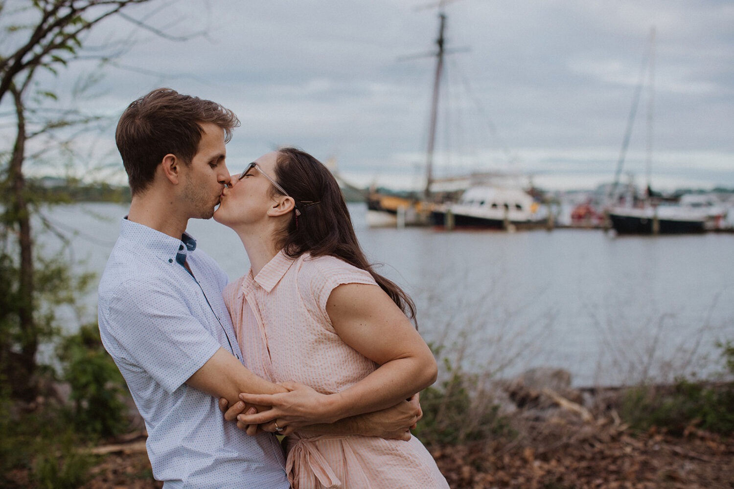 couple kisses by water at Old Town Alexandria waterfront engagement session