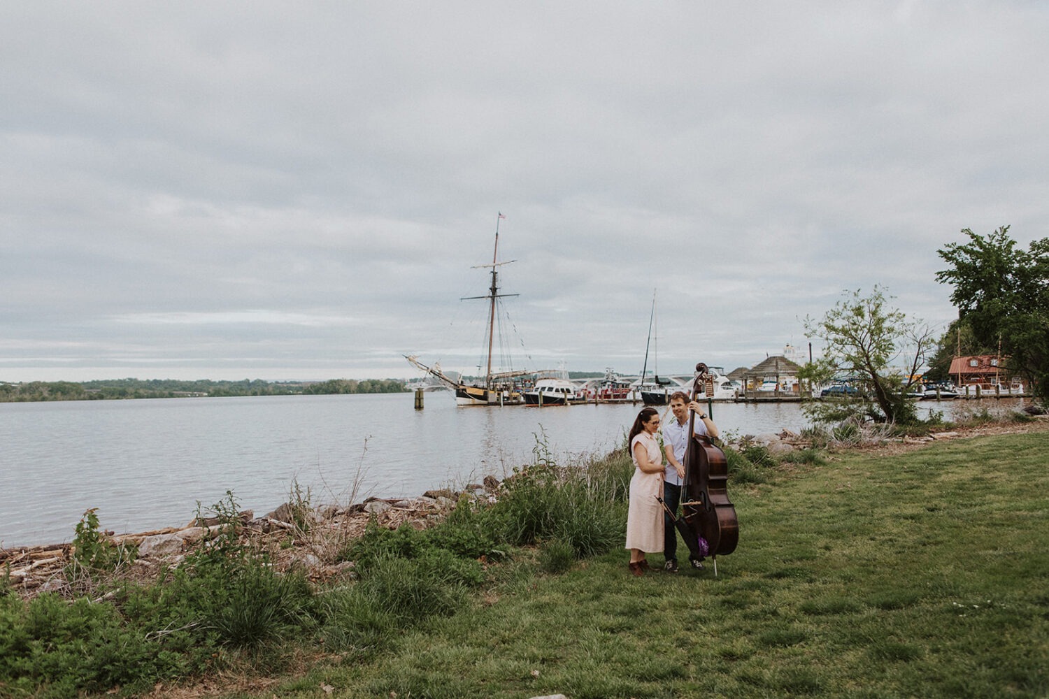 groom plays bass instrument at Old Town Alexandria waterfront engagement session