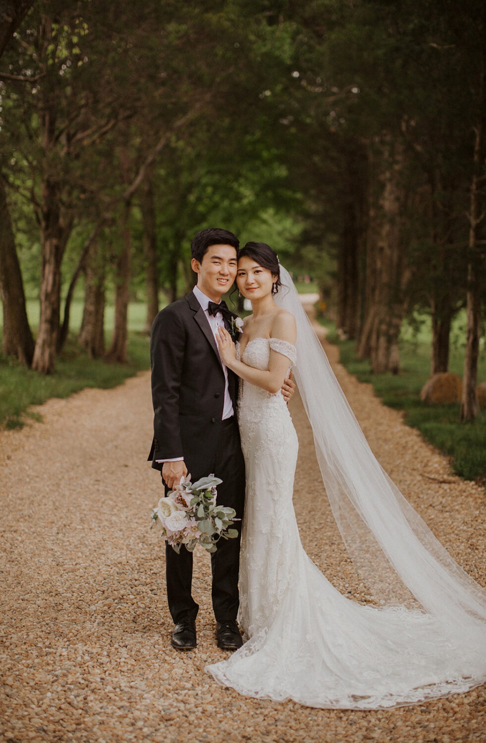 couple stands in tree-lined path at Virginia wedding venue