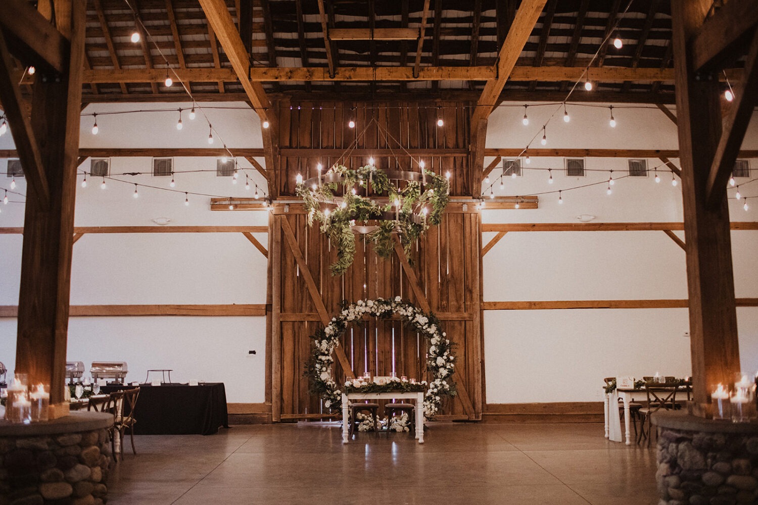 white flowers, candles and greenery as table decor at barn wedding reception