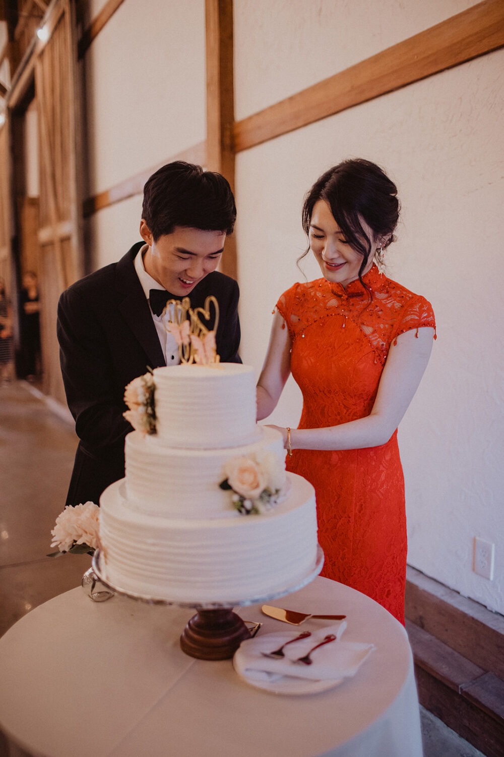 couple cuts cake at barn wedding reception 