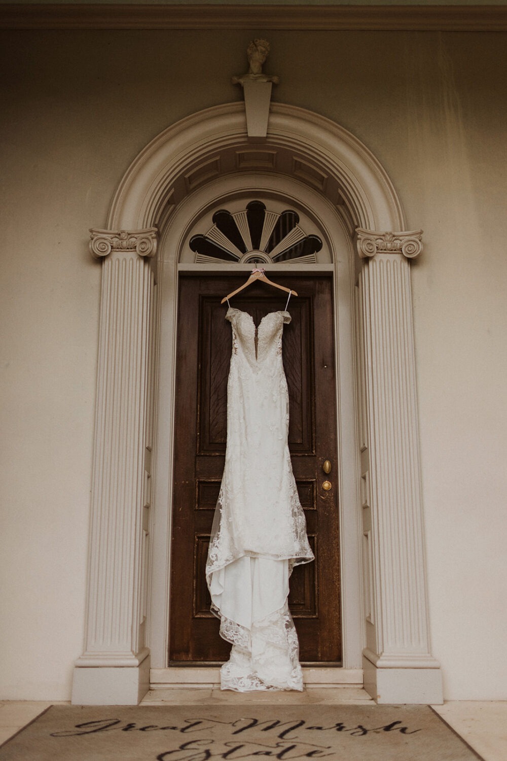 white wedding dress hangs on doorway
