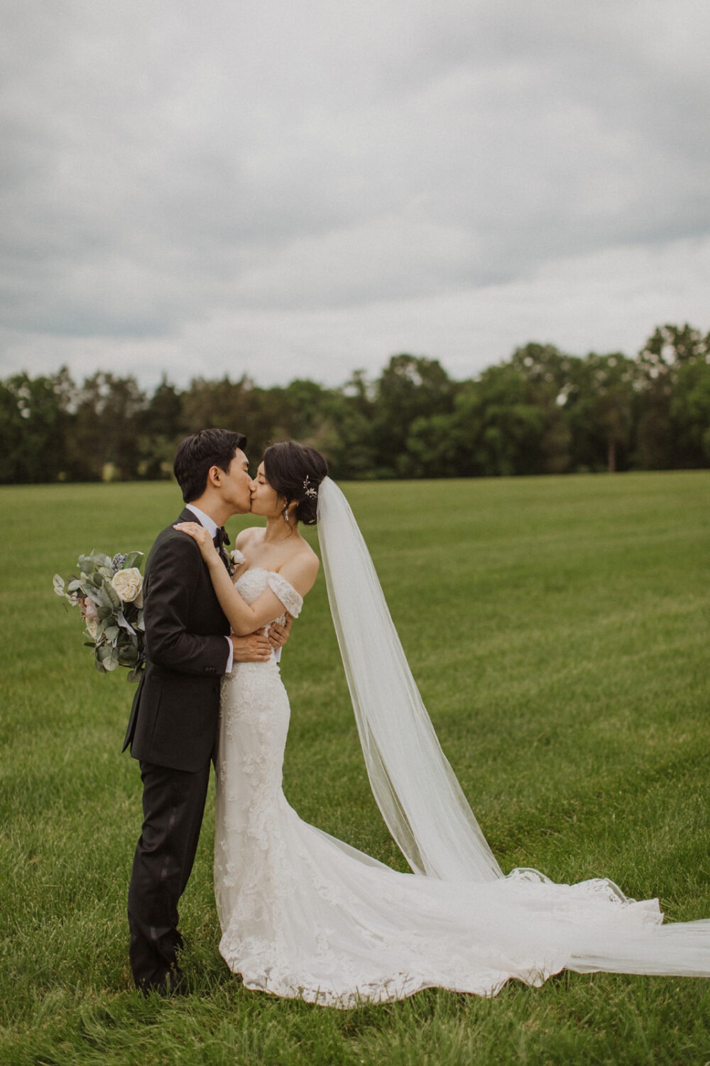couple kisses in grassy meadow at Virginia wedding venue