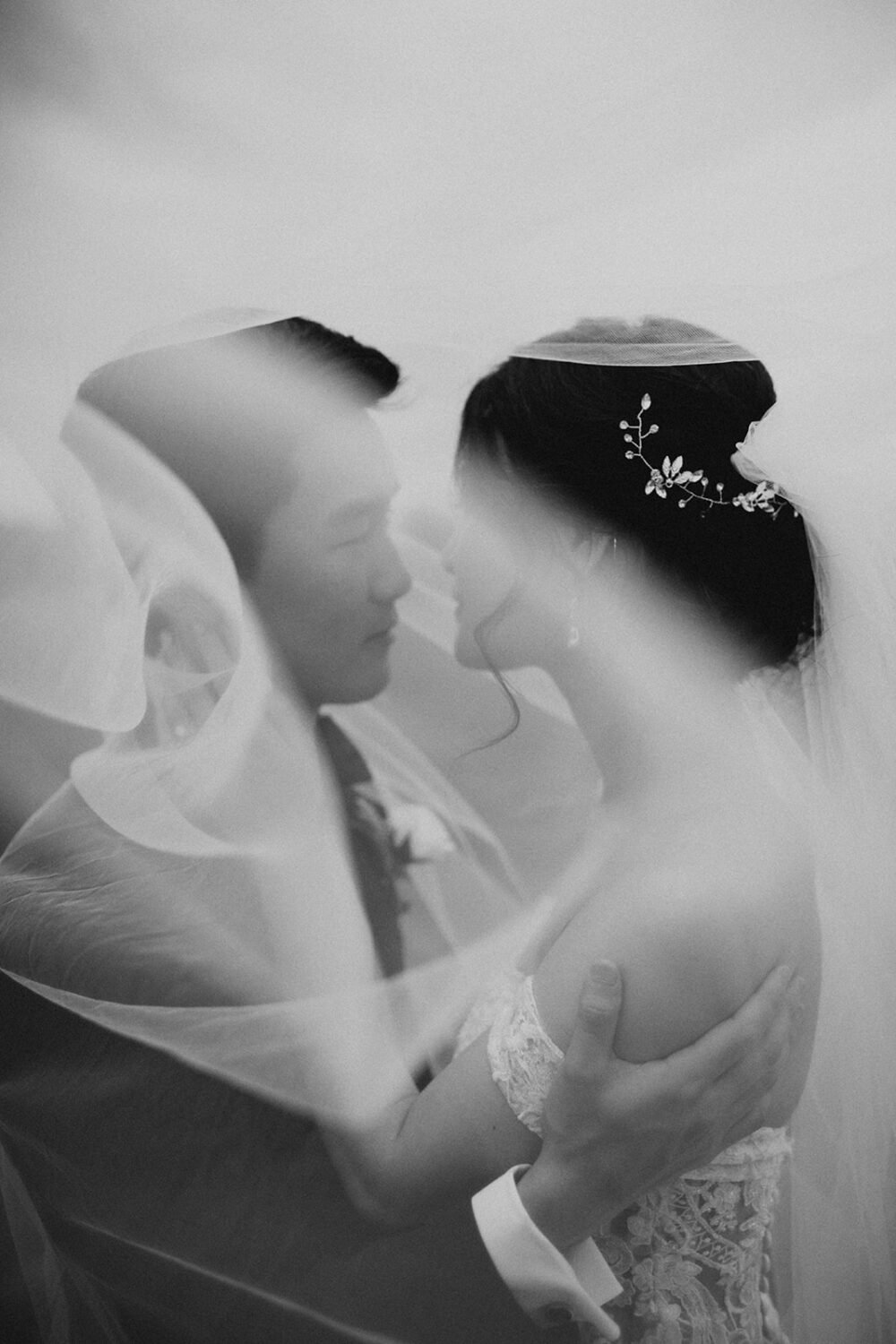 couple embraces under wedding veil 