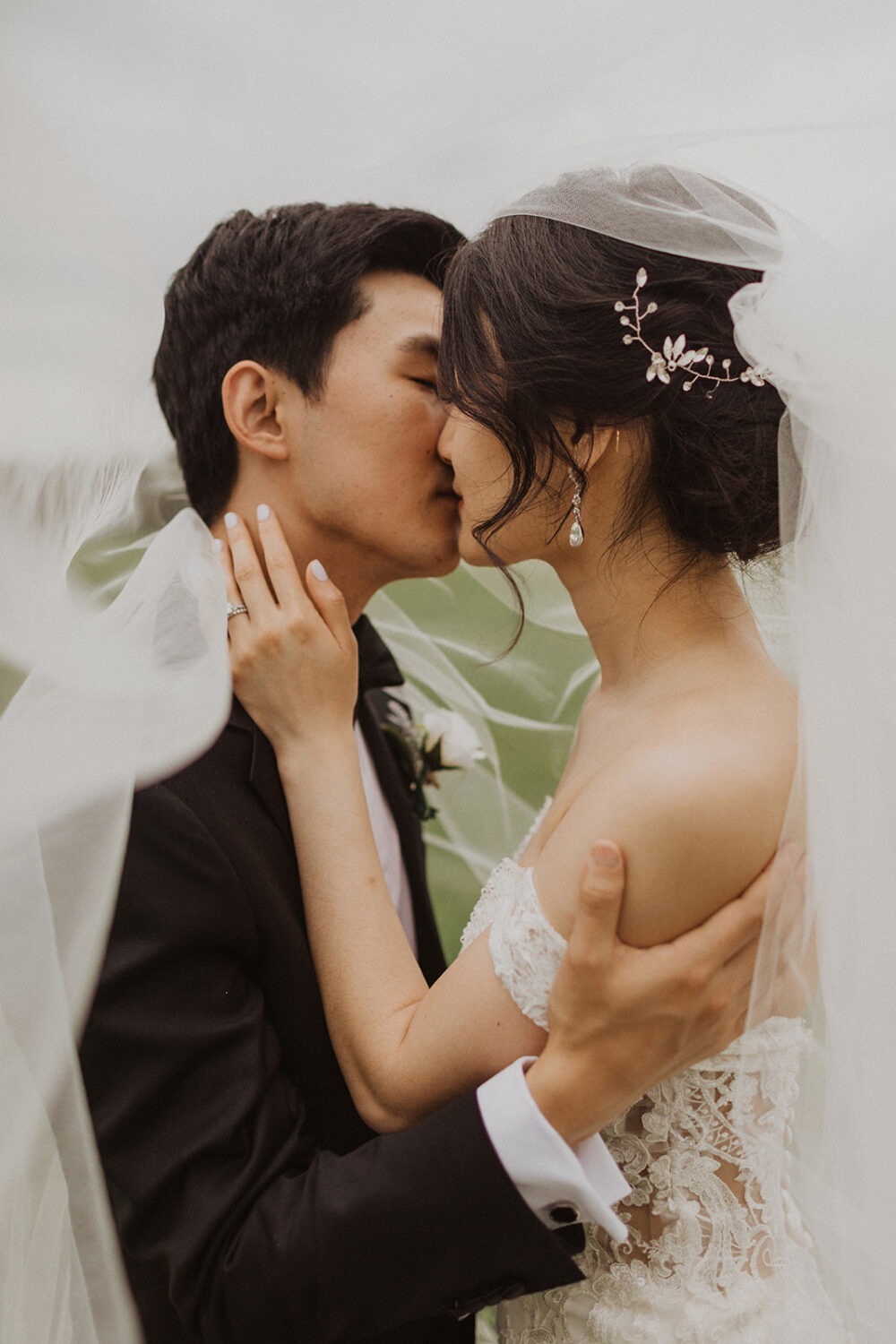 couple kisses under wedding veil 