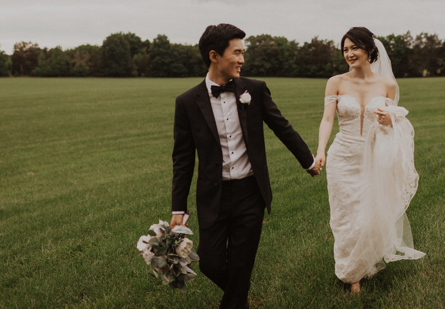 couple walks down through grassy field at Virginia wedding venue