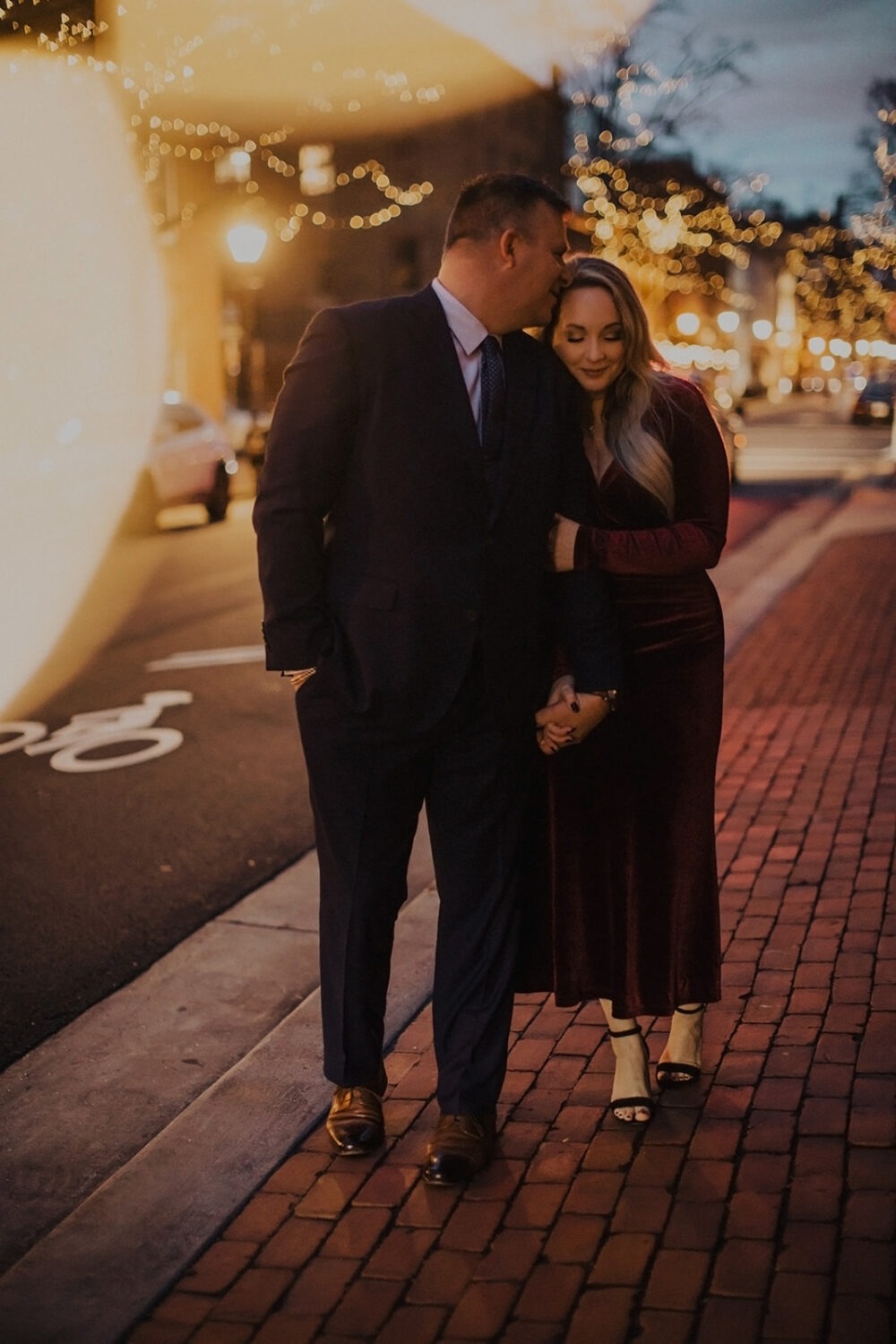 couple walks through twinkle light street at engagement session