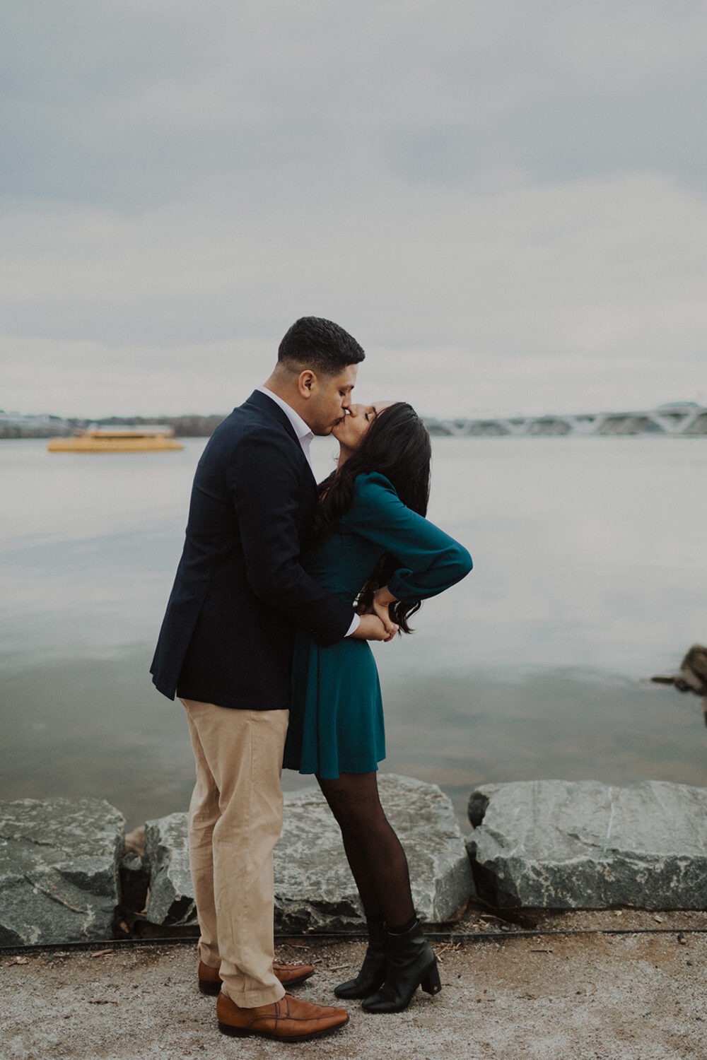 couple kisses by river at waterside engagement session