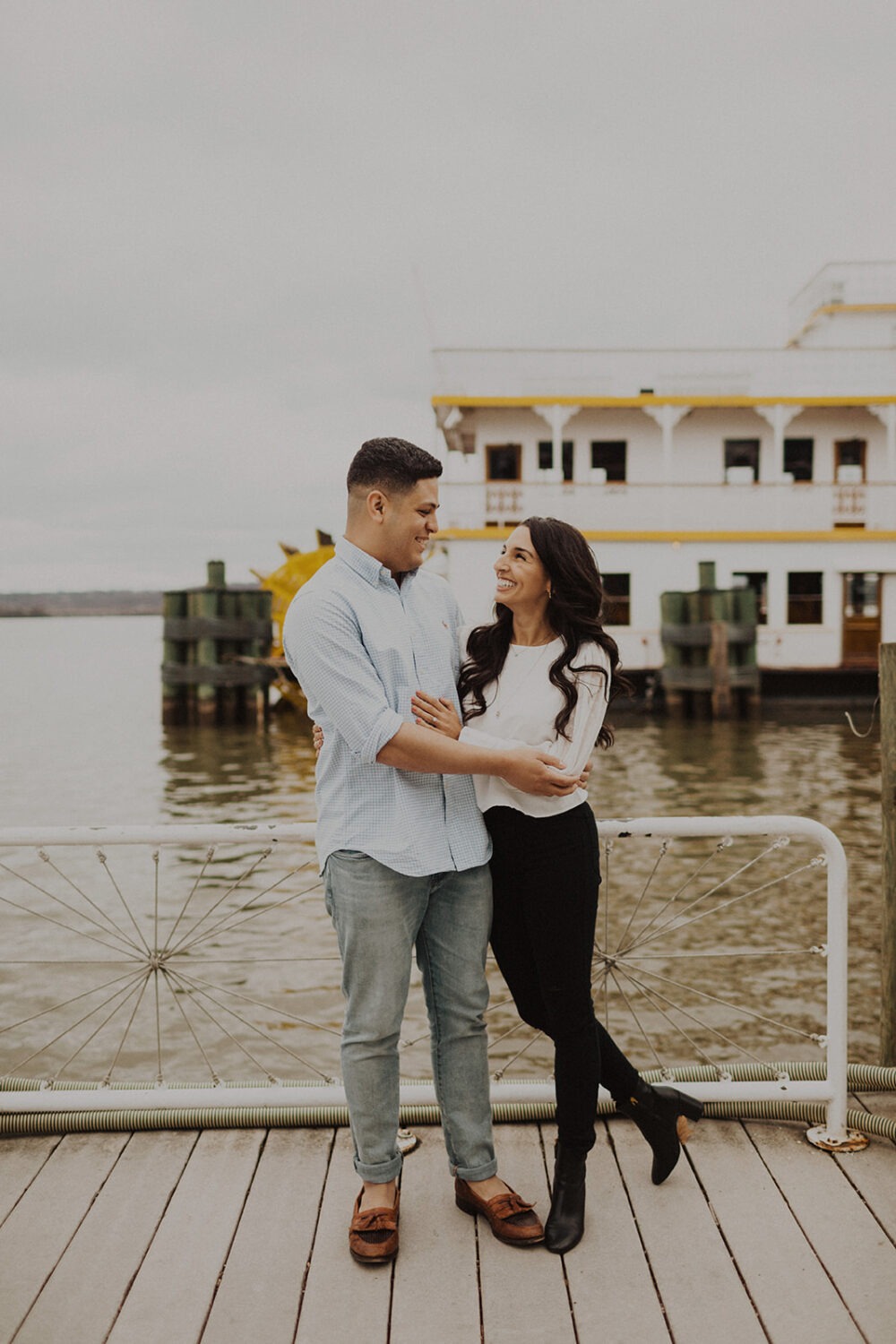 couple embraces on pier at Old Town Alexandria waterfront engagement session