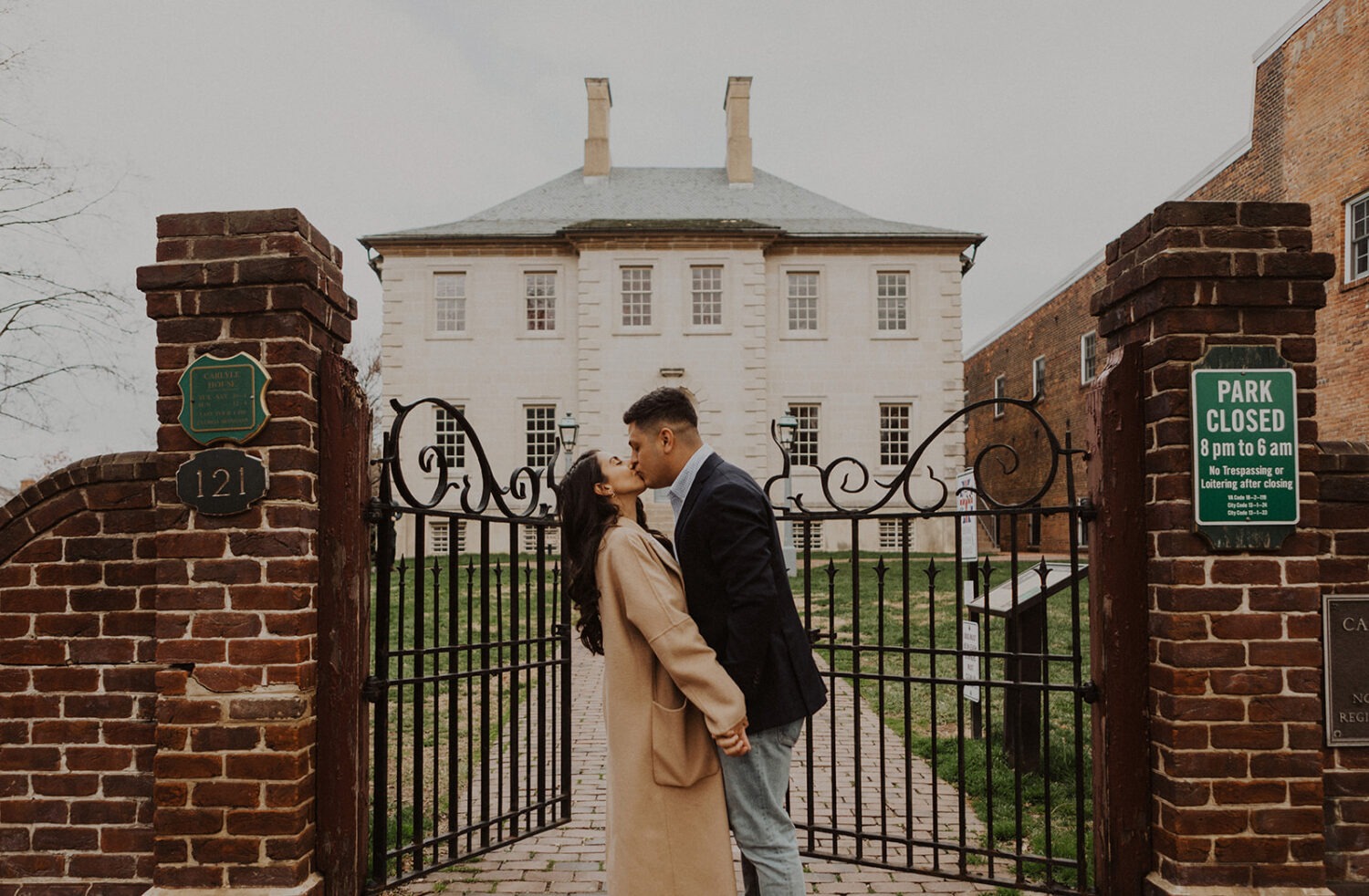couple kisses in front of iron gate at Old Town Alexandria engagement session