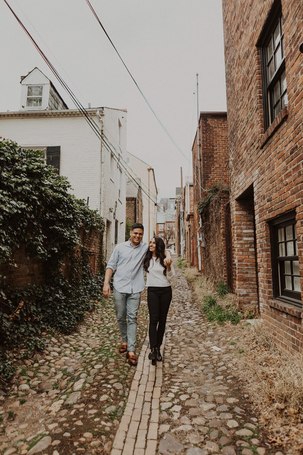 couple walks through alleyway at old town alexandria engagement session