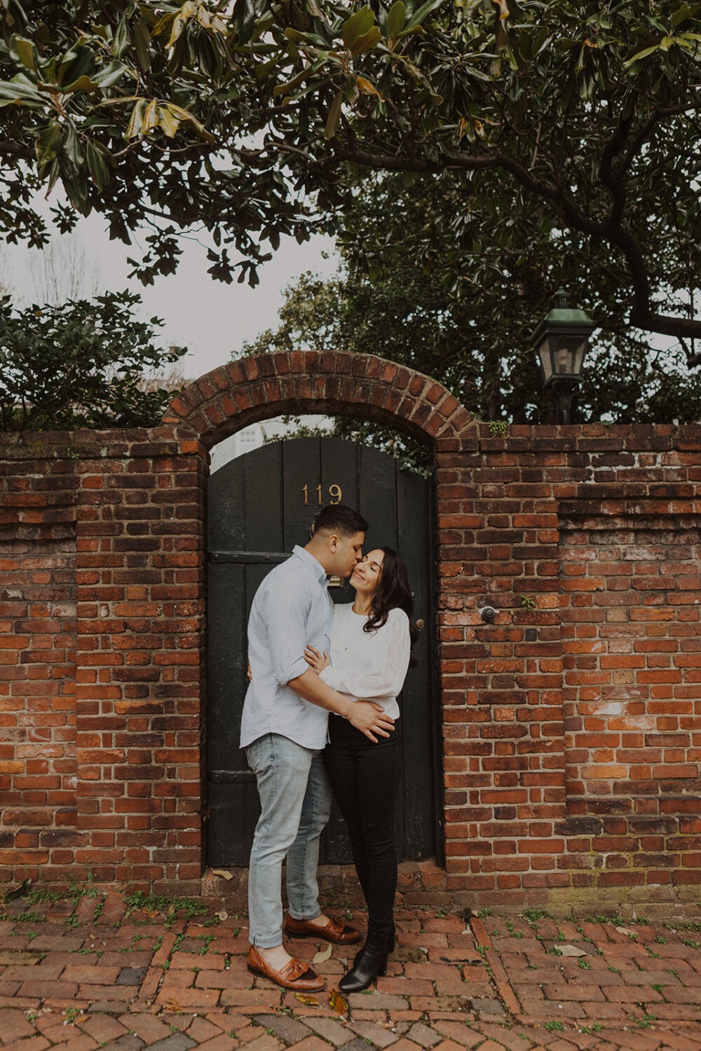 couple stands in front of brick wall at old town alexandria engagement session
