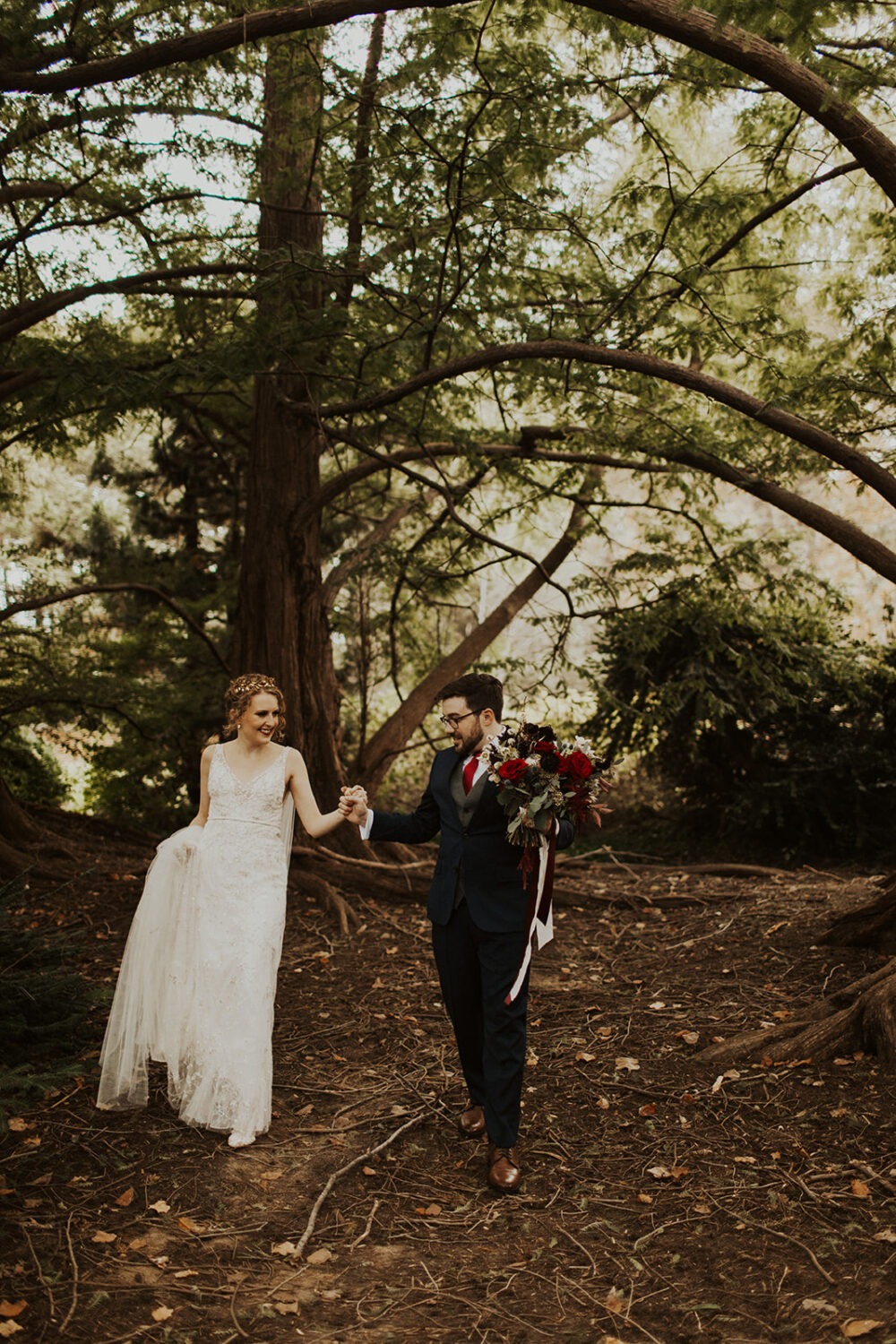 couple walks through forest holding hands during first look 