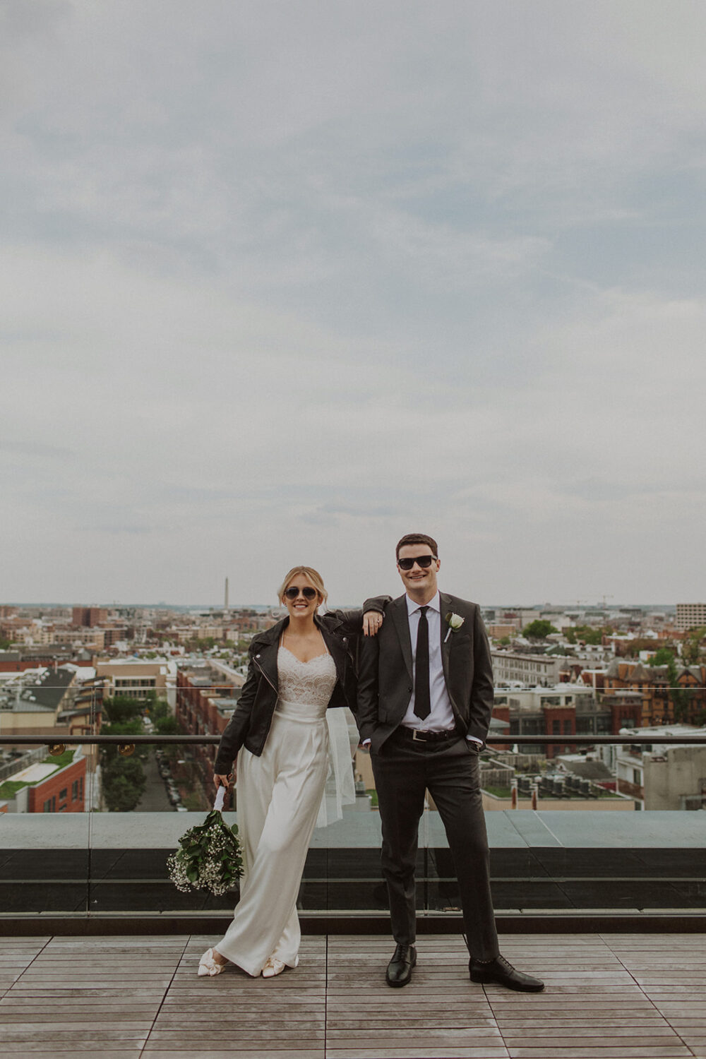 couple stands on rooftop at DC elopement wearing sunglasses 