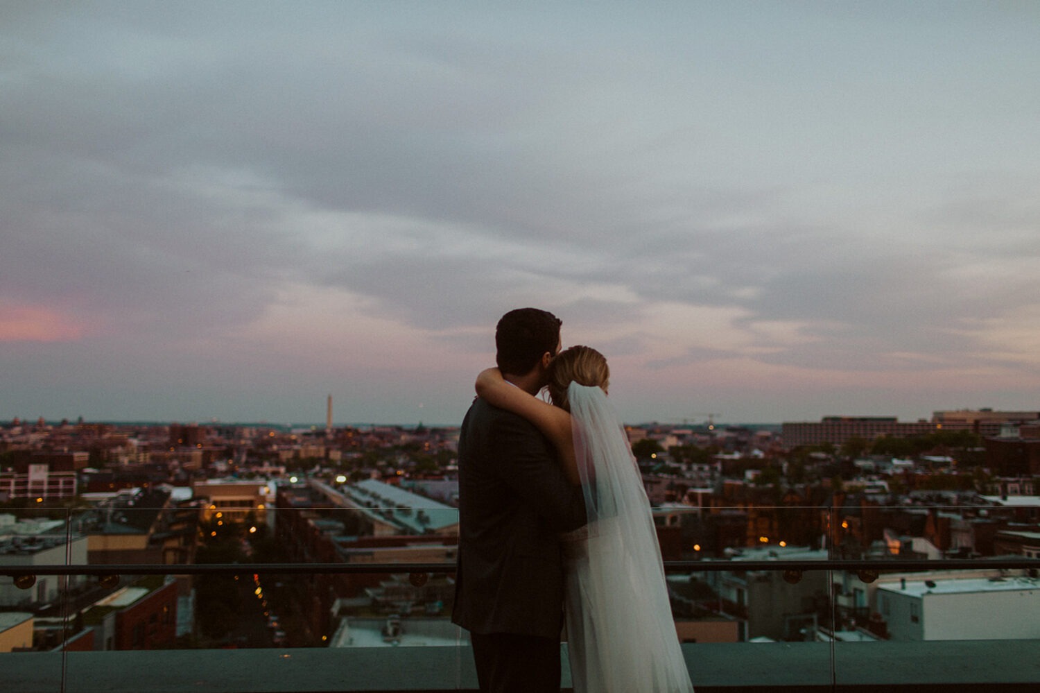 couple embraces at sunset on DC rooftop wedding venue 