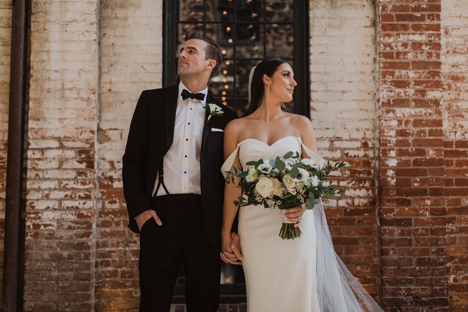 couple holds hands standing in front of brick wall at Mt. Washington Mill Dye House wedding venue