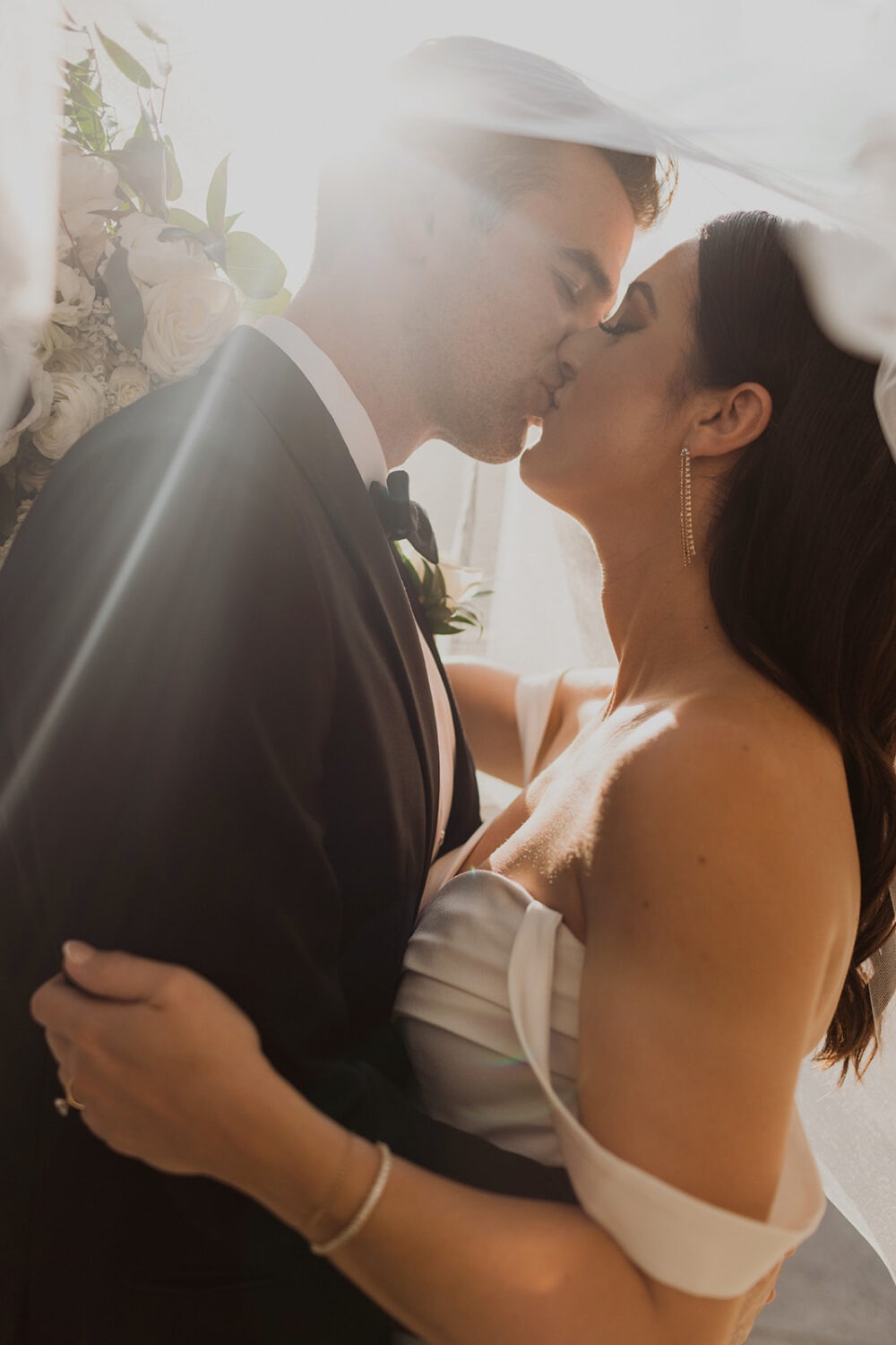 couple kisses under wedding veil at Mt. Washington Mill Dye House wedding venue