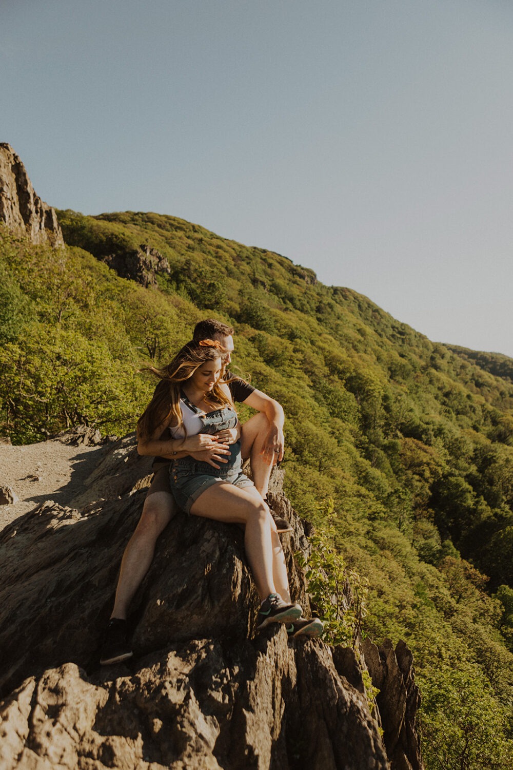 couple sits on rock embracing at sunset couples adventure