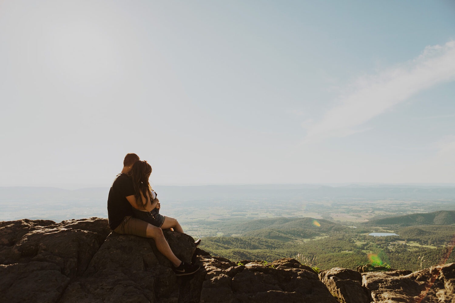 Couples embraces seated on top of mountain in Shenandoah National Park