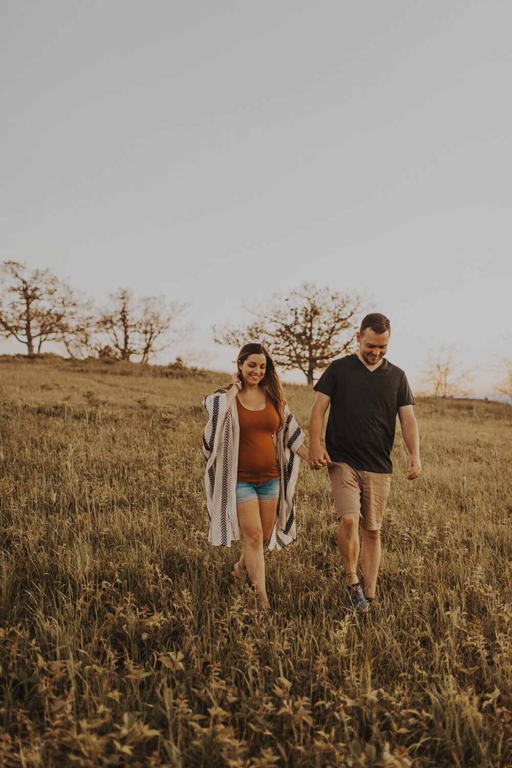 couple walks holding hands through field at sunset couples adventure