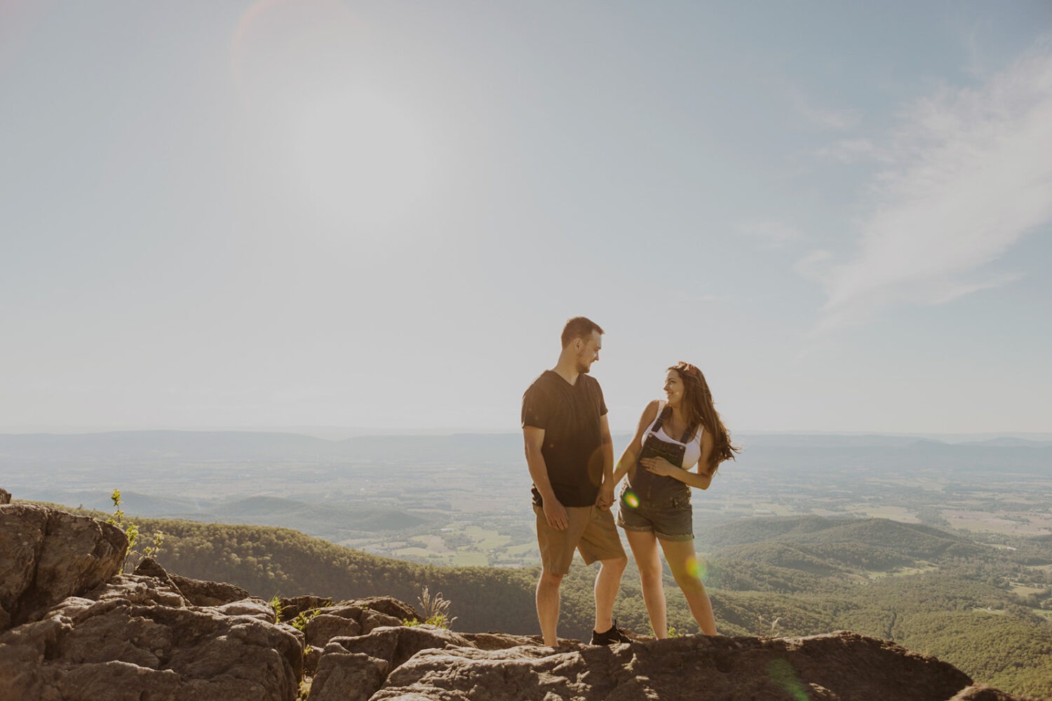 Couples stands holding hands on top of mountain in Shenandoah National Park