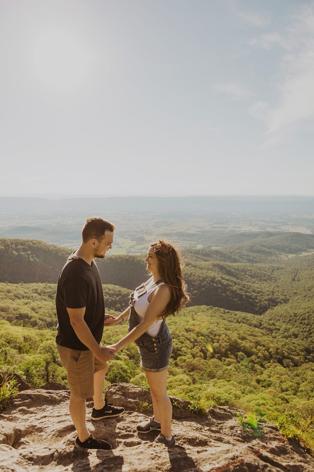 couples holds hands on top of mountain in Shenandoah National Park