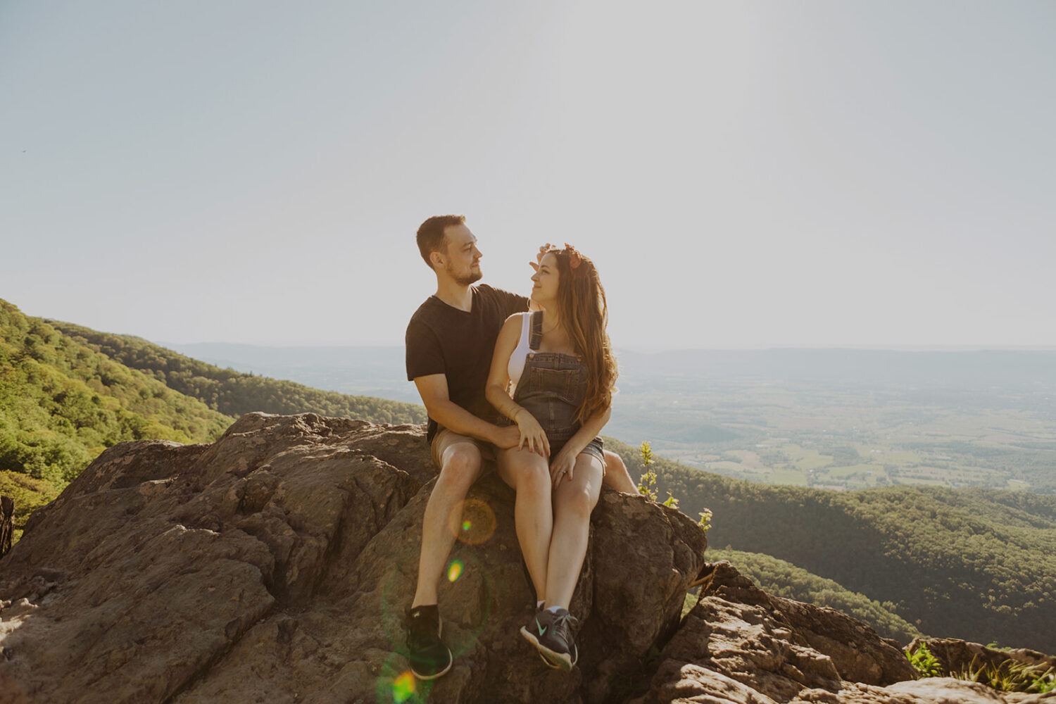 couple sits on rock embracing at sunset couples adventure