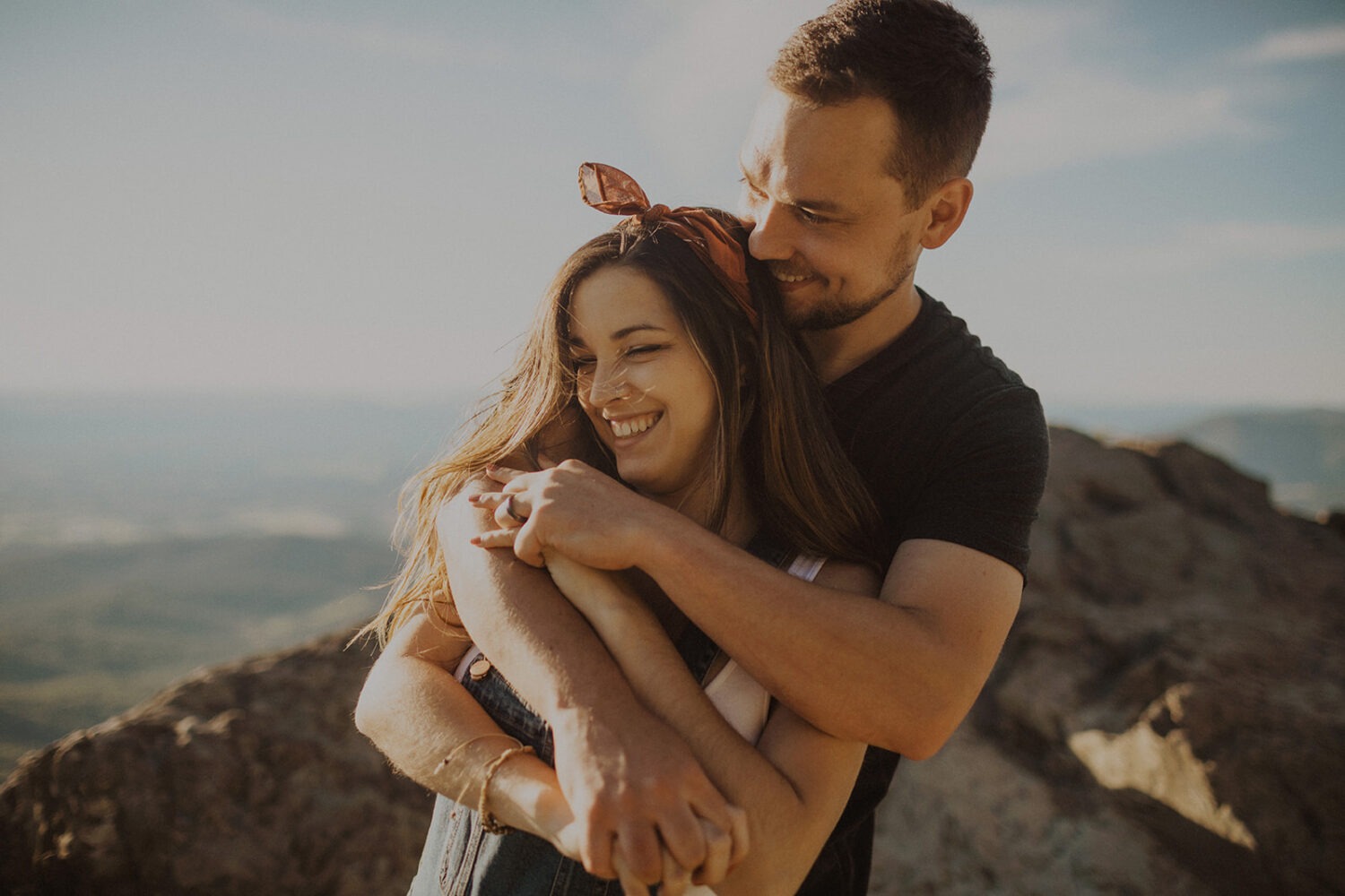 couple embraces on mountaintop at sunset maternity session 