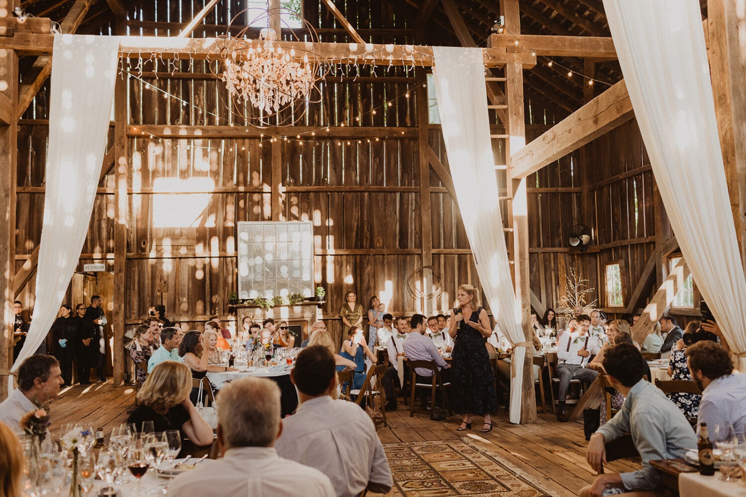 wedding guests seated at rustic barn wedding reception 