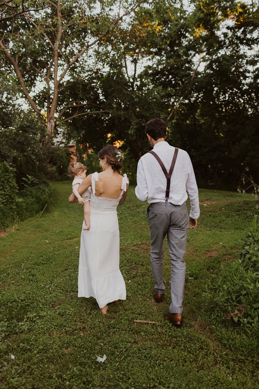 couple walks holding baby together rustic outdoor wedding