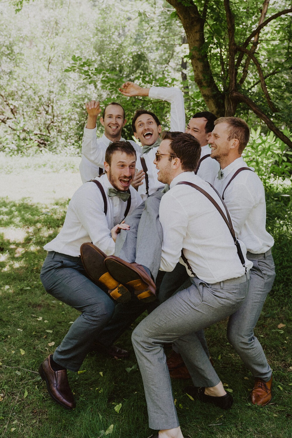 groomsmen throw groom up into the air pulling from barn wedding ideas 
