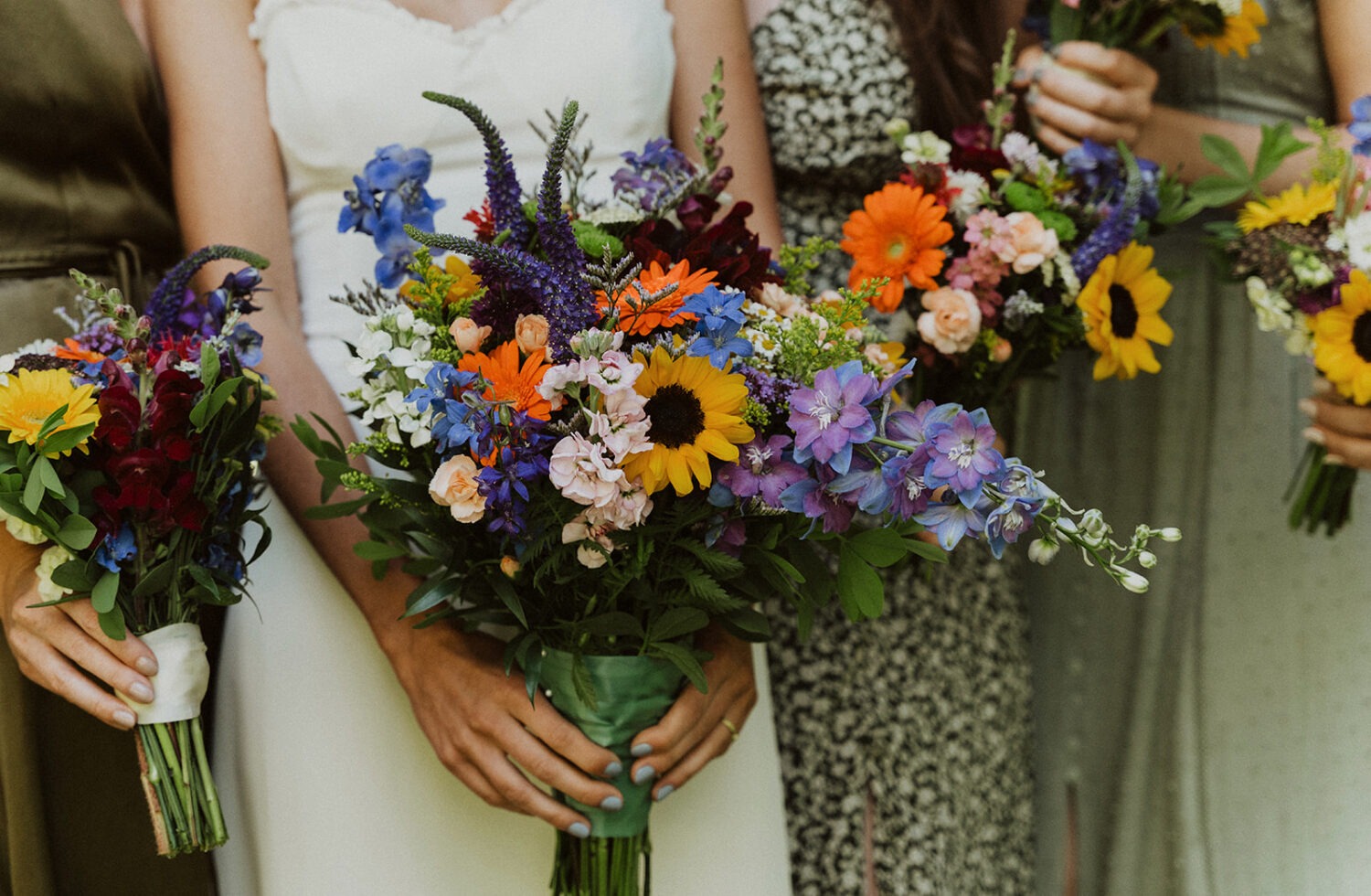 bride and bridesmaids hold colorful wildflower bouquets