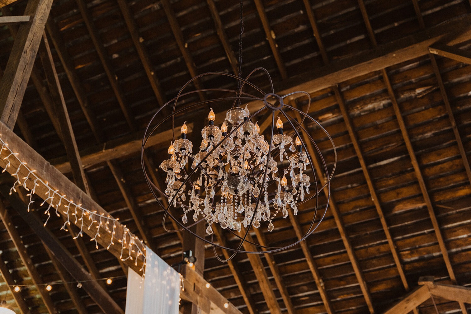 chandelier hanging from rustic barn ceiling 