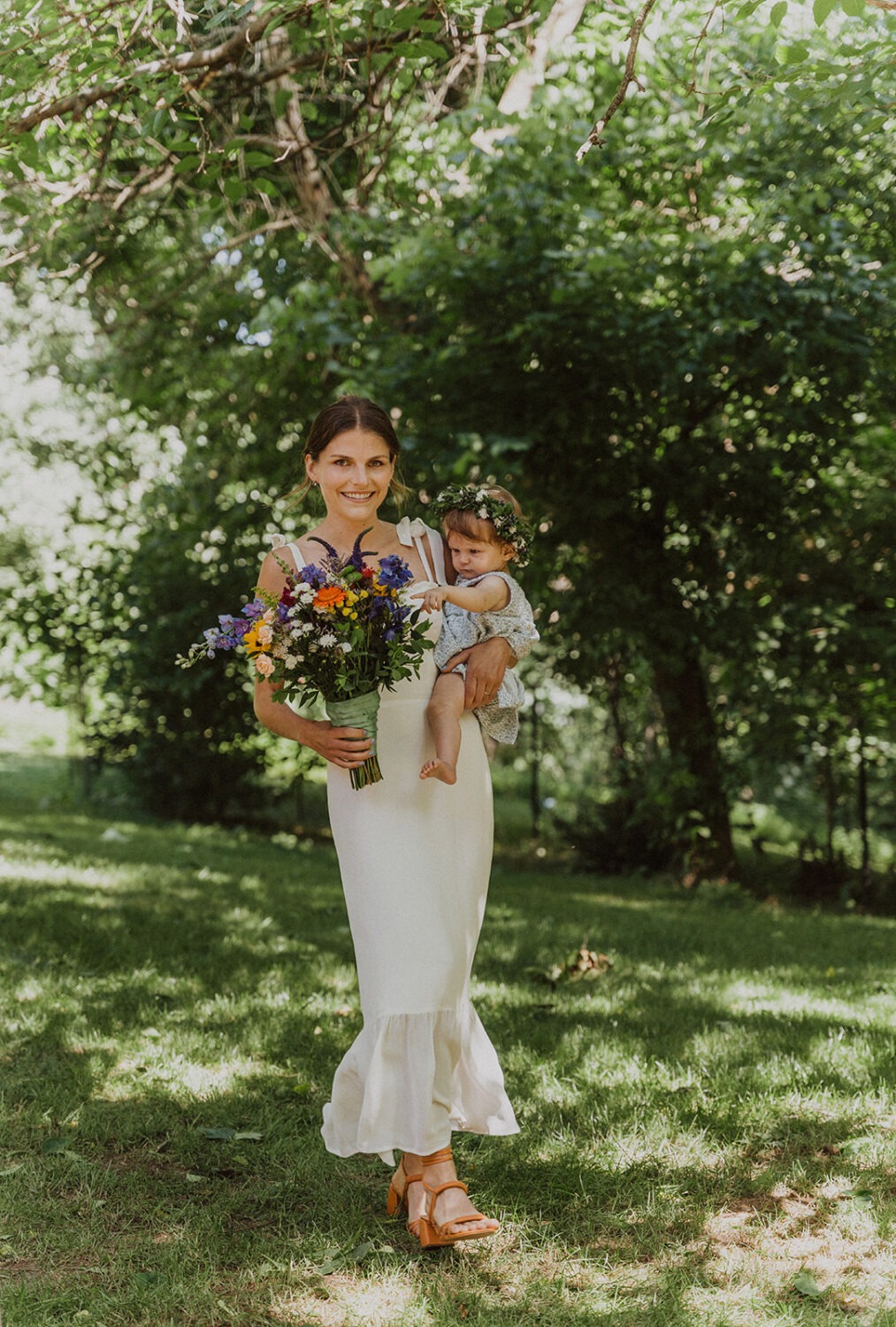 bride carries baby down aisle at outdoor rustic wedding
