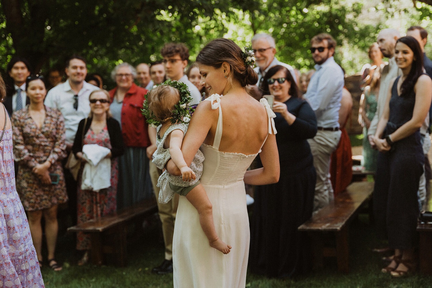 bride carries baby down aisle at outdoor rustic wedding