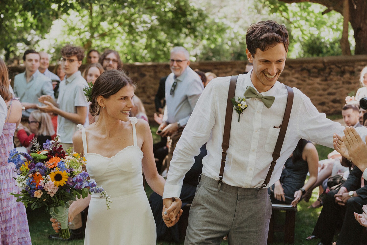 couple walks holding hands at rustic outdoor wedding 