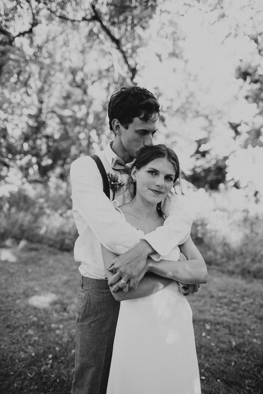 couple embraces at outdoor wedding under trees