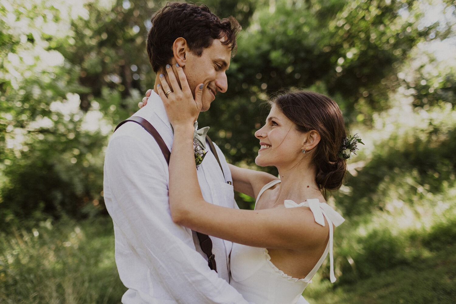 bride holds groom's face at rustic outdoor wedding 