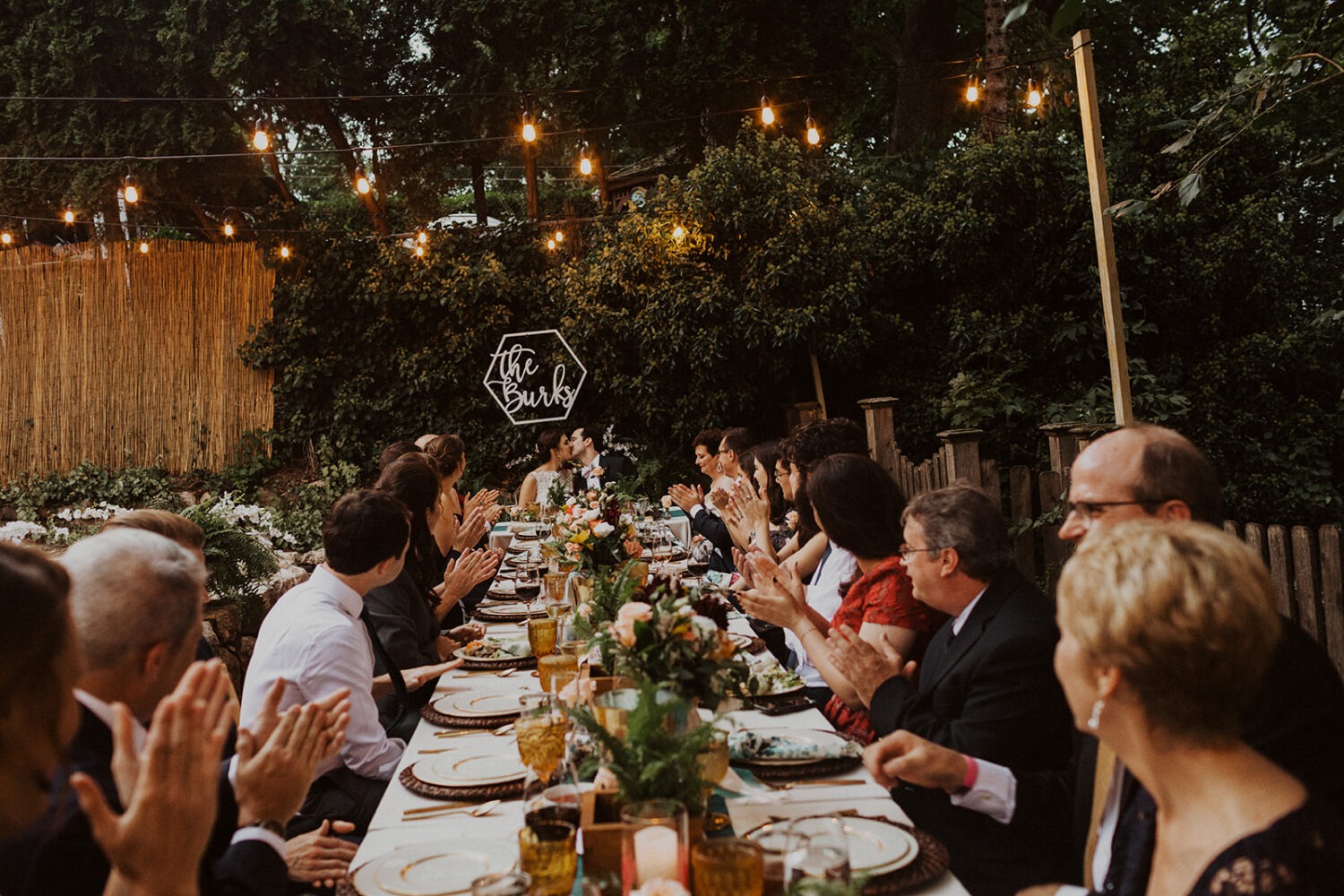 guests clap at table in backyard wedding reception 