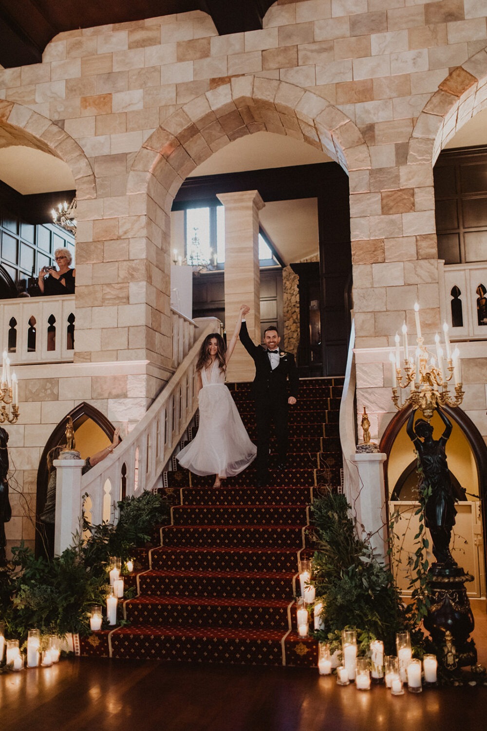 couple walks down staircase into wedding reception 