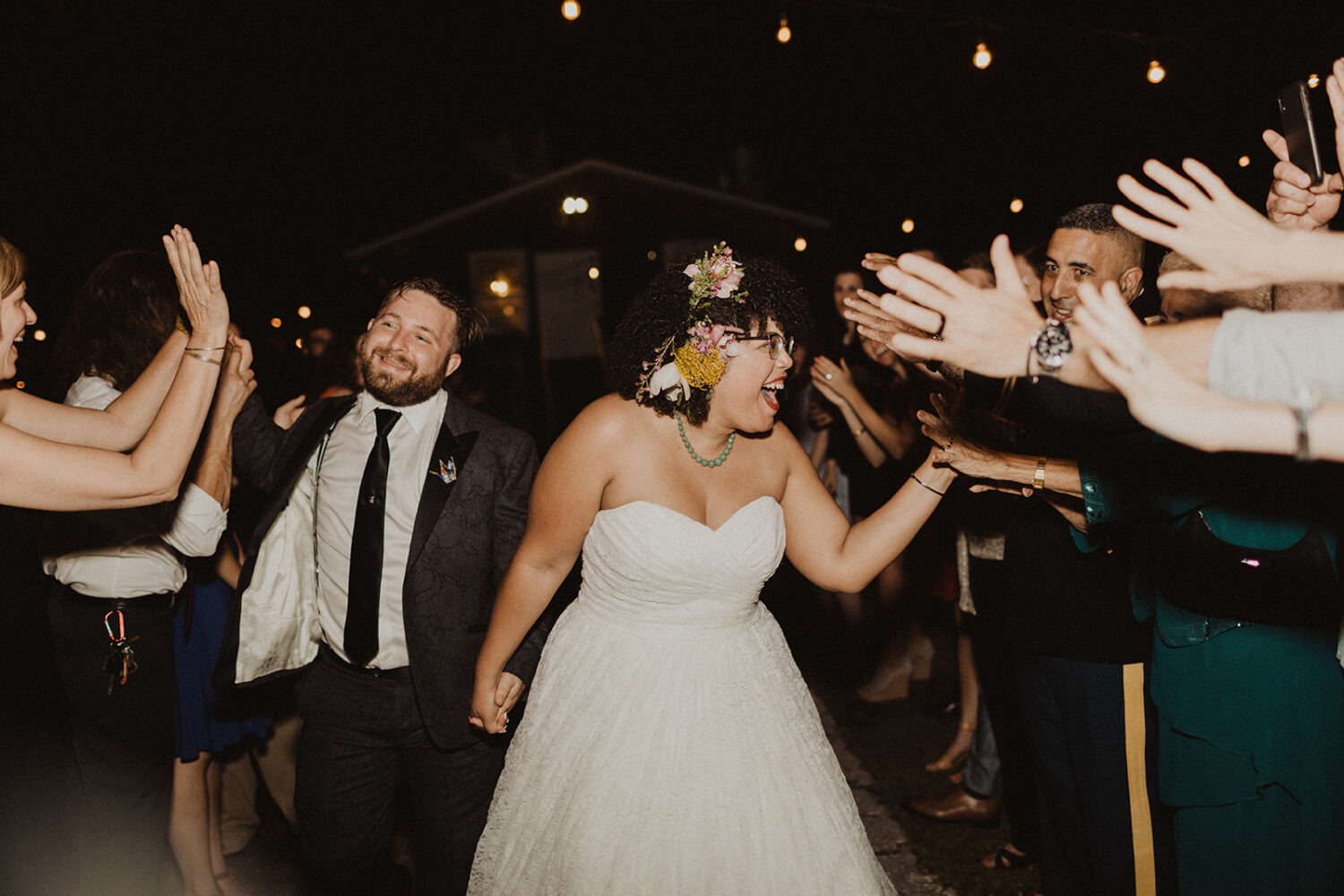 couple exits wedding waving to guests at summer wedding 