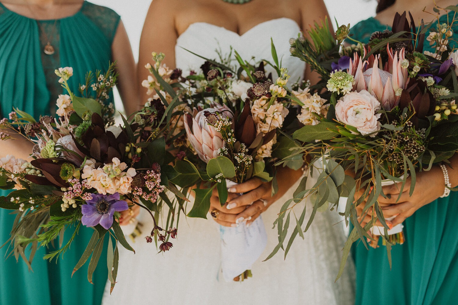 bridesmaids and bride hold tropical flower bouquets at summer wedding