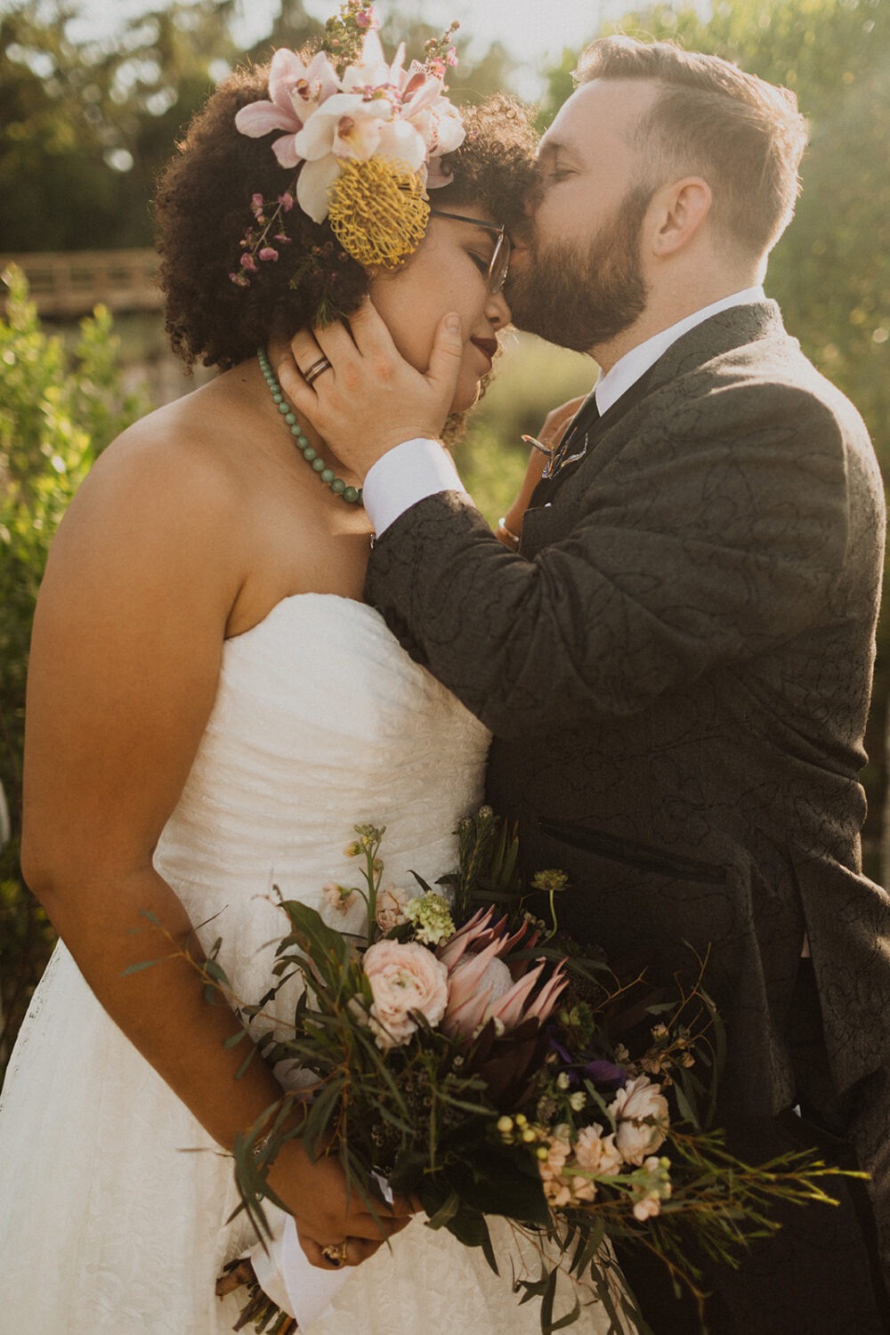 groom kisses bride's forehead at summer wedding