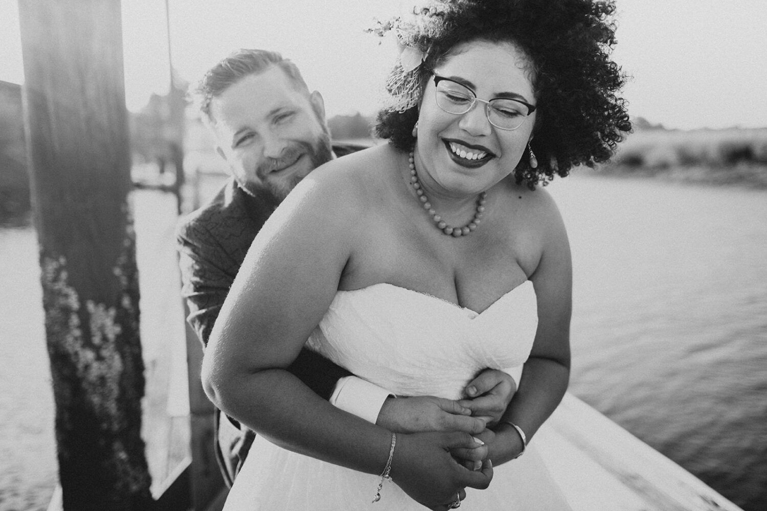 couple embraces on dock at waterfront wedding