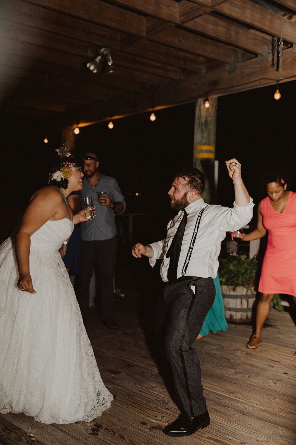 couple dances with guests at sunset waterfront wedding
