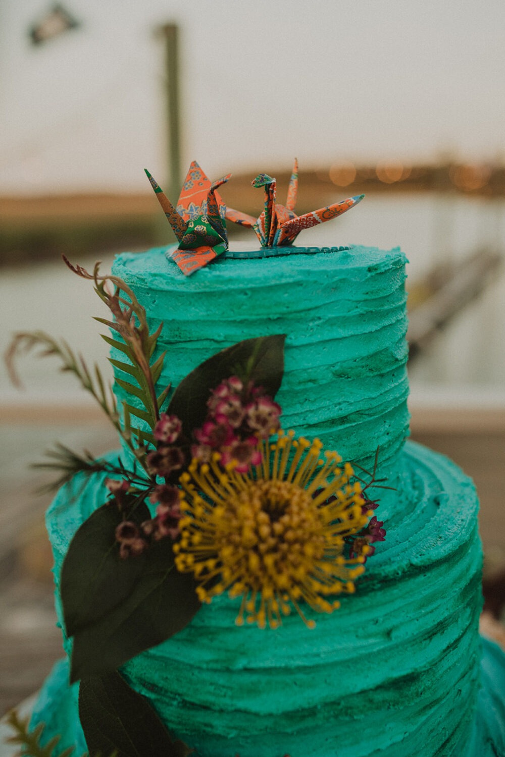 paper cranes on top of blue tropical flower wedding cake