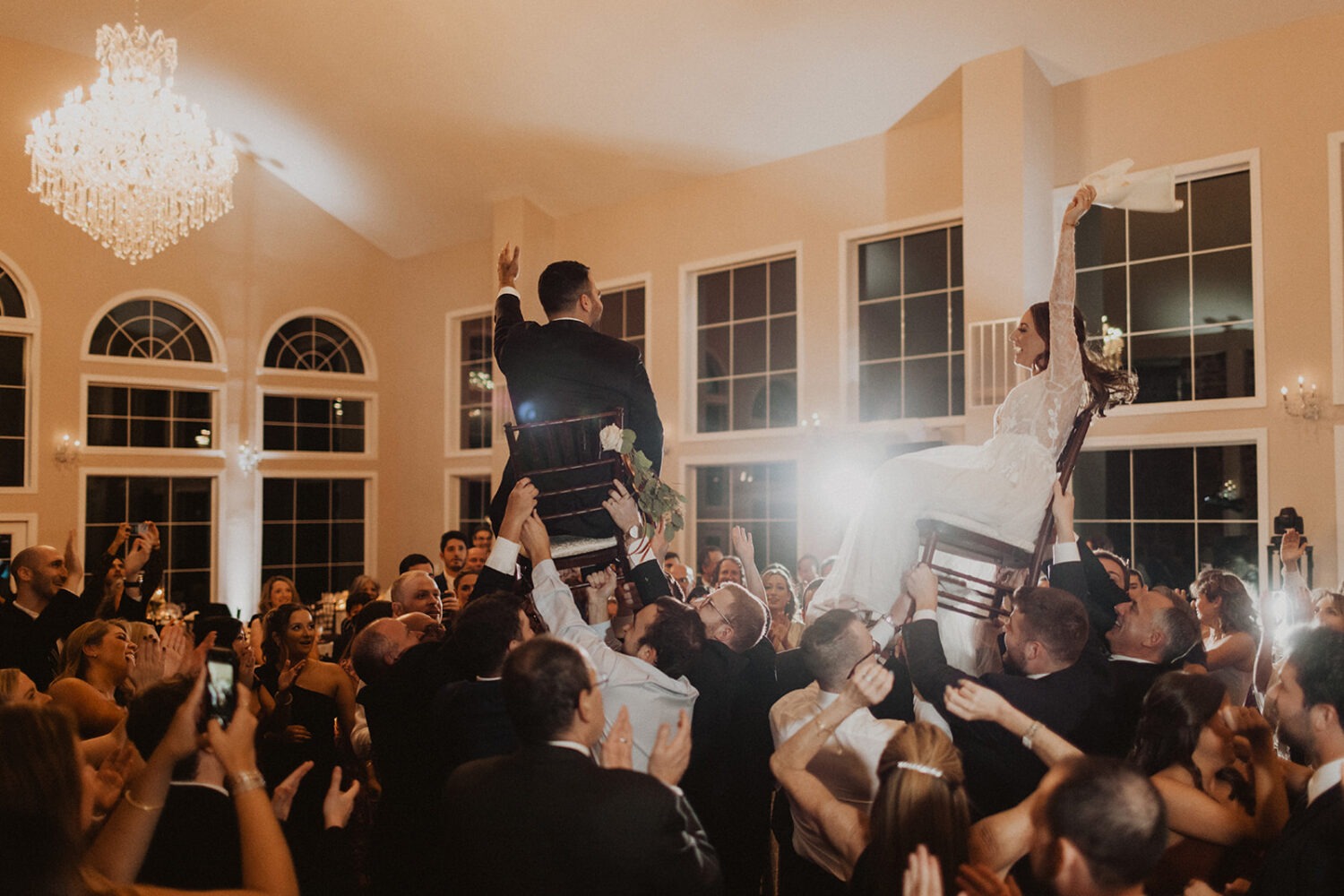 couple carried on chairs during reception at traditional Jewish wedding
