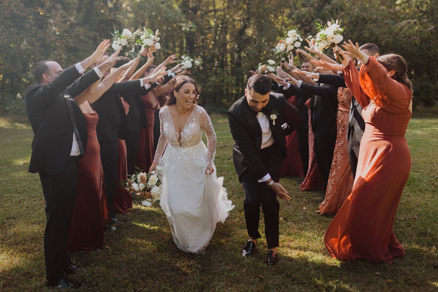 couple dances through wedding party arch at outdoor wedding